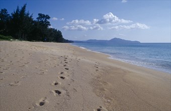 THAILAND, Phuket , Mai Khao Beach, View north west along empty sandy beach with lines of footprints