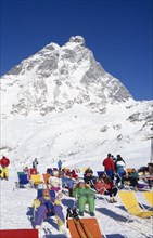 ITALY, Valle d’Aosta, Breuil Cervina, Group of skiers sunbathing at the foot of the Matterhorn.