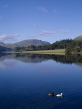 ENGLAND, Cumbria, Lake District, Buttermere.  View north-west with tree covered landscape reflected