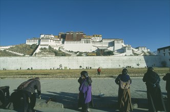 CHINA, Tibet, Lhasa, Potala Palace on the hillside with row of pilgrims prostrating themselves in