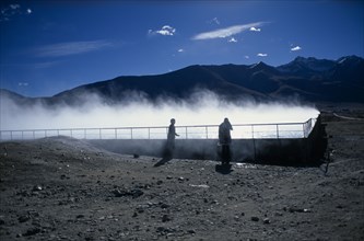 CHINA, Tibet, Lhasa, Yangpachen geothermal powerstation with two women stood beside a pool of