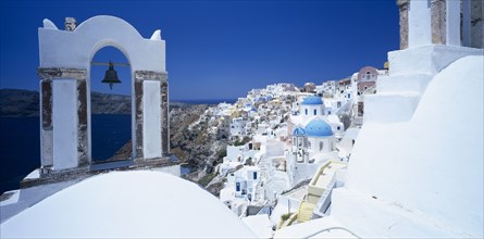 GREECE, Cyclades Islands, Santorini, Oia.  White painted hill town with bell in foreground hanging