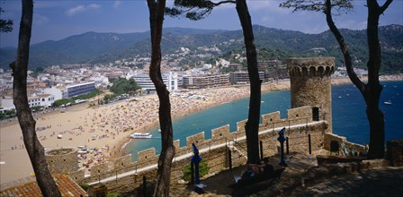 SPAIN, Catalonia, Tossa de Mar, View over busy sandy beach and town from fortified walls of Villa