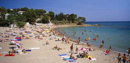 SPAIN, Catalonia, Llanca, "Curved, sandy beach with people sunbathing and in the sea.  White