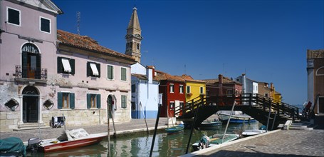 ITALY, Veneto, Venice, "Burano Island.  Bridge and canal with boats moored to posts along each side
