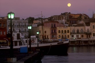 GREECE, Crete, Hania, Venetian Port.  Moored boat and quayside buildings with moon in pale purple