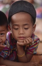 THAILAND, North, Mae Sai, Burmese Karen refugee child in camp looking down with his chin in his
