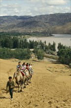 CHINA, Ningxia, Yellow River, People on traveling up hill on camels