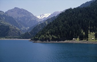 CHINA, Xinjiang, Heaven Lake, View over lake toward pine forests covering mountainous landscape
