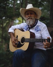USA, Texas, Bandera, Bearded cowboy on the Mayan Ranch playing acoustic guitar