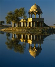 INDIA, Rajasthan, Jaisalmer, Gadi Sagar Tank.  Building reflected in water.