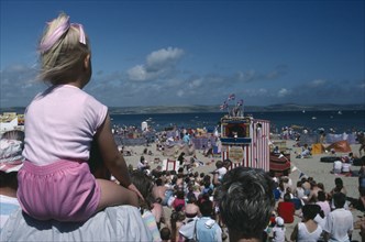ENGLAND, Dorset , Weymouth, View over crowds on the beach viewing Punch and Judy show with girl in