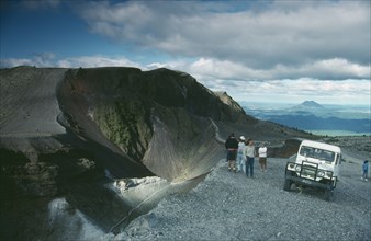 NEW ZEALAND, North Island, Mount Tarawera, Jeep and visitors parked beside crater rim of volcano.