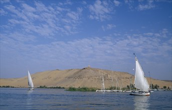 EGYPT, Upper Egypt, Aswan, Qubbet el-Hawa and The Tombs of The Nobles with two feluccas sailing