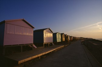 ENGLAND, Kent, Whitstable, View along a row of beach huts painted different colours on Whitstable