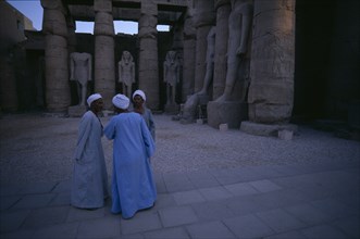 EGYPT, Upper Egypt, Luxor, Group of three men talking inside the temple of Luxor Statues in