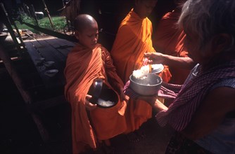 CAMBODIA, Religion, Young monks being served rice Alms.