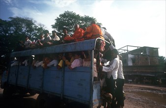 CAMBODIA, Kompong Chhnang, "Crowded public bus, passengers sitting on roof and holding on to back