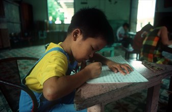 VIETNAM, Ho Chi Minh City, Child writing at desk in an Agent Orange orphanage.