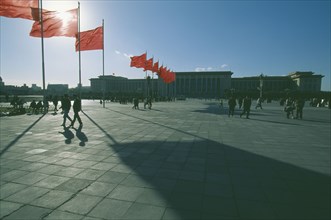 CHINA, Beijing, Tiananmen Square, Great Hall of The People in silhouette with sun behind flying