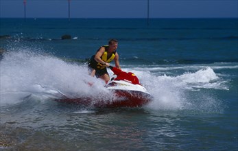 20002912 SPORT Watersports Jet Ski Man riding a jet ski on the sea at Littlehampton in West Sussex  England.