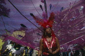 ENGLAND, London, "Notting Hill Carnival, dancer in pink and red costume following a float."