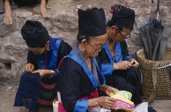 LAOS, Luang Prabang, Hmong women in traditional dress doing embroidery.