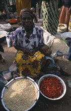 NIGERIA, Enugu, Woman selling chillies and pulses at a market stall