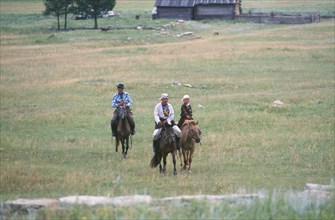 MONGOLIA, Khentii Province, Horsemen riding away from building