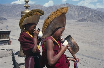 INDIA, Ladakh, Thikse Gompa, Monks at the monastery blowing horns