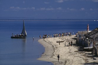 MOZAMBIQUE, Pemba, Fishing boat off the coast and waiting crowd of people on sandy beach with