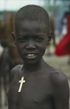 SUDAN, South, Kongor, Dinka boy.  Head and shoulders portrait wearing cross on string around neck.