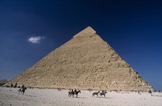 EGYPT, Cairo Area, Giza, Pyramid of Khufu with horse and donkey renters passing by