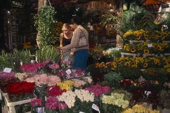 HOLLAND, Noord, Amsterdam, Women standing among a display at the Flower Market