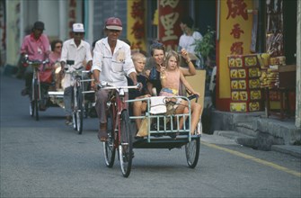 MALAYSIA, Melaka, Tourists on bicycle rickshaw in the Chinatown district of the former trading port
