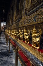 THAILAND, Bangkok, Grand Palace with Perspective of golden figures at side of Temple of Emerald