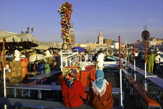 MOROCCO, Marrakech, Djemaa El Fna. Food stall with two customers seated in the foreground