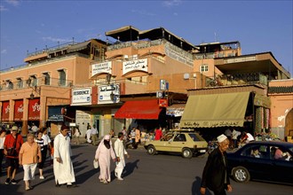 MOROCCO, Marrakech, Street scene with row of shops and passing tourists and traffic