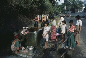 MYANMAR, Yangon, Washing at roadside tap.