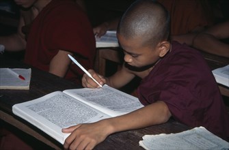MYANMAR, Insein, Ywama Monastery.  Young monks studying at wooden desk.