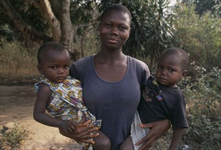 GHANA, Accra, Woman holding twin infants in her arms.