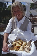 SWEDEN, Oaxen Island, Smiling woman holding a basket of Swedish bread at Oaxen Skargards Krog