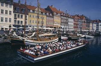 DENMARK, Zealand, Copenhagen, Nyhavn Canal. Cruise boat passing sailing boats moored on the