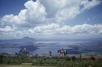 PHILIPPINES, Luzon Island, Taal Lake, Tourists being led on horses along shores of lake in volcanic