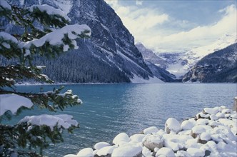 CANADA, Alberta, Banff National Park, Lake Louise and steep pine covered mountainside in snow.