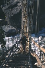 NEPAL, Himalayas, Figure crossing suspension bridge over Kali Gandaki River