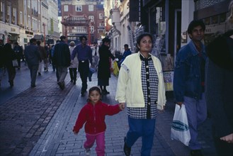 ENGLAND, London, Chinatown.  Mixed crowd of shoppers with young family in foreground.