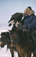 CHINA, Xinjiang Province, Kazakhs, Kazakh man on horseback with eagle used for hunting