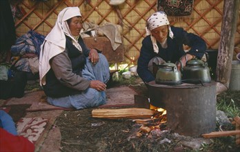 CHINA, Xinjiang Province, Kazakhs, Kazakh nomadic women brewing tea in their Kigizuy or felt tent