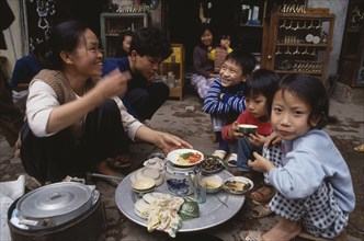 VIETNAM, North, Hanoi, Woman and children having a meal from a tray on the pavement outside their